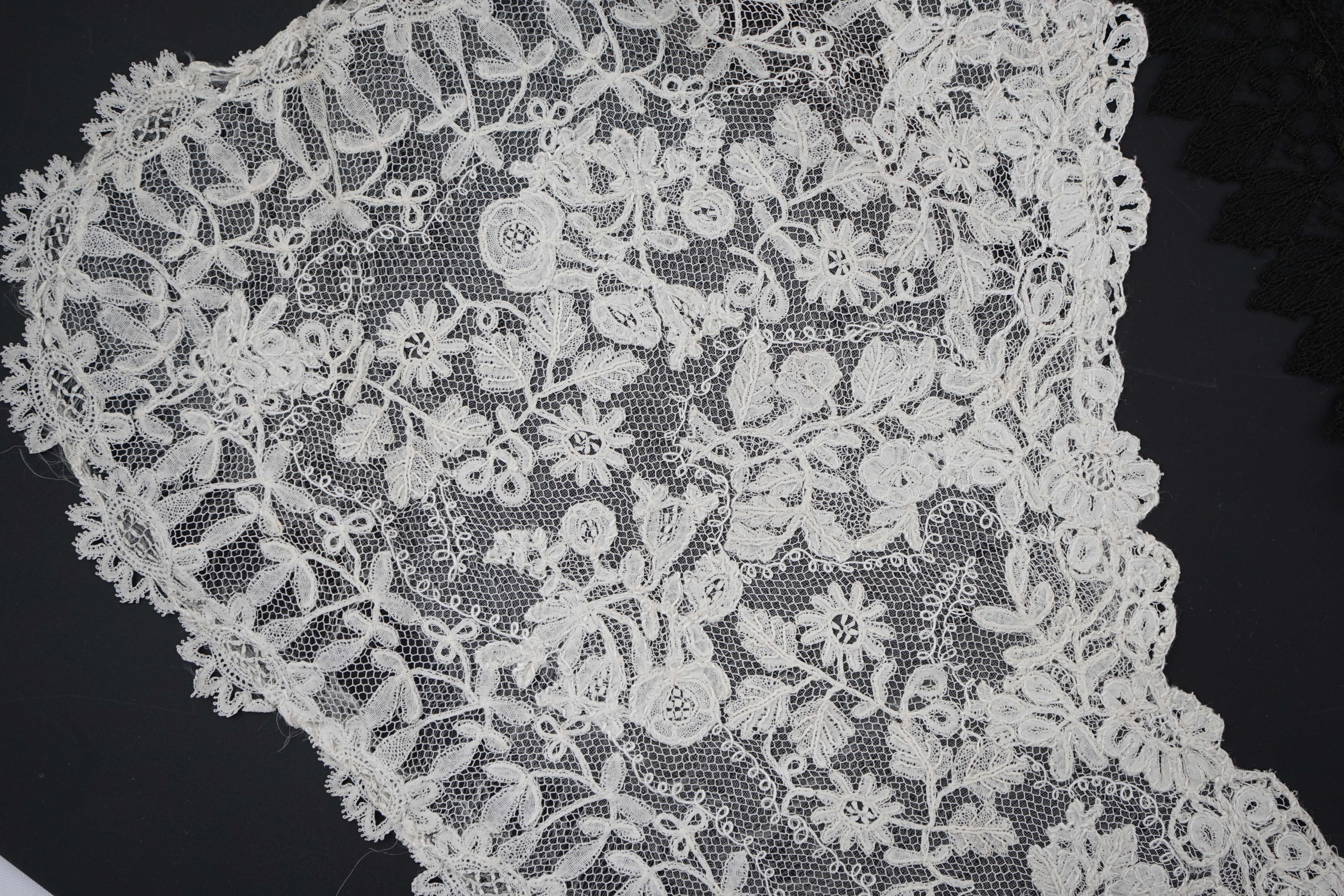 A small collection of late 19th century laces including a cream Brussels bobbin lace collar appliquéd on to net and two similar Brussels bobbin lace lappets, a pair of cream Honiton bobbin lace cuffs and a black lace fal